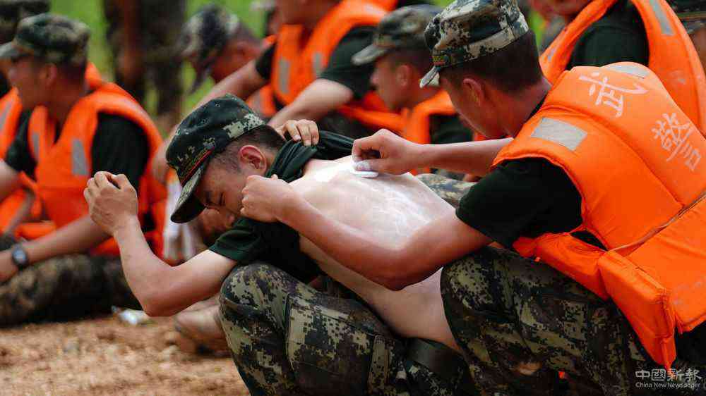 7月11日，在江西省鄱陽縣江家?guī)X村，武警戰(zhàn)士在執(zhí)行抗洪任務的休息間隙互相涂抹藥粉，連日奮戰(zhàn)讓許多戰(zhàn)士長痱子或曬傷。新華社記者 周密 攝