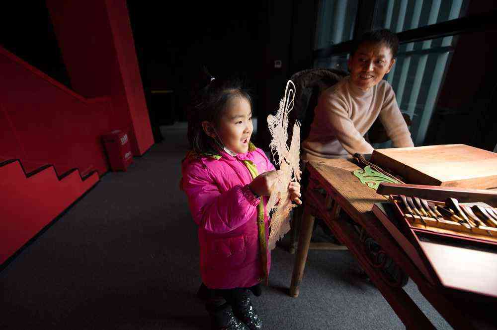 1月7日，在陜西西安明清皮影藝術(shù)博物館，一名前來參觀的小女孩拿起一幅先前雕刻好的皮影骨架。